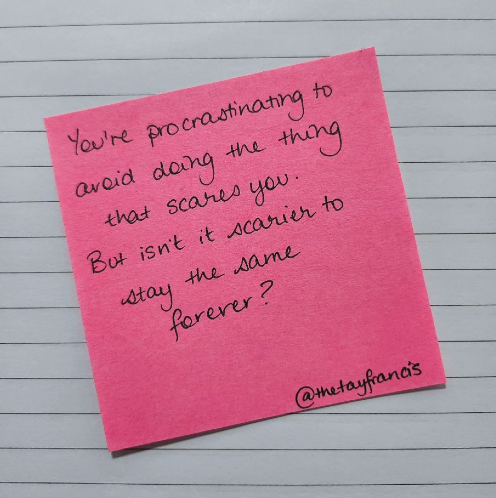 Pink post-it note on white lined page with text: You're procrastinating to avoid doing the thing that scares you. But isn't it scarier staying the same forever?
